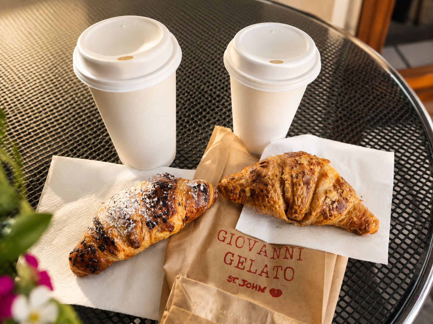Two coffees with almond and chocolate croissants on a cafe table