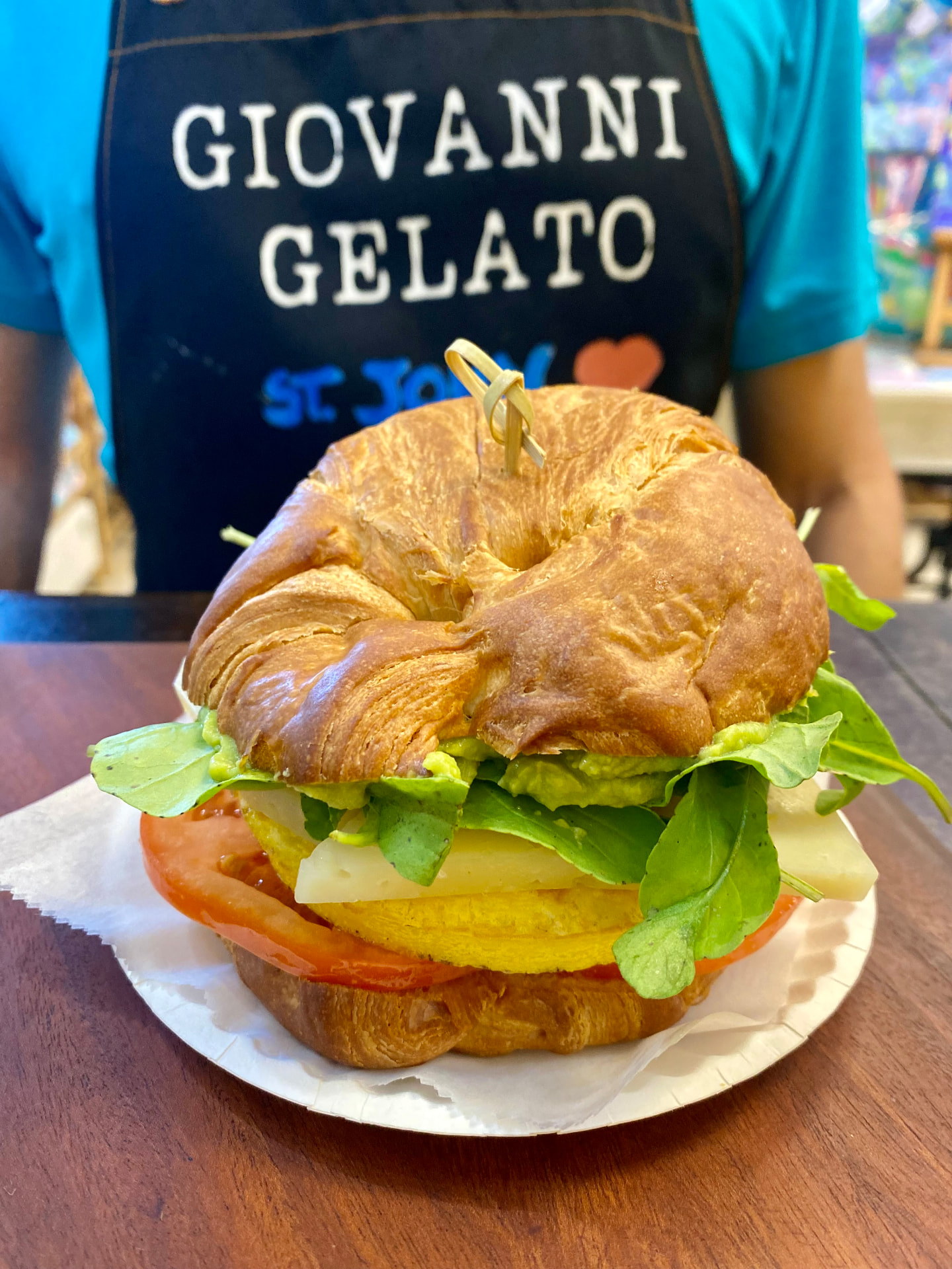 Croissant breakfast sandwich with arugula, tomato, cheese and avocado